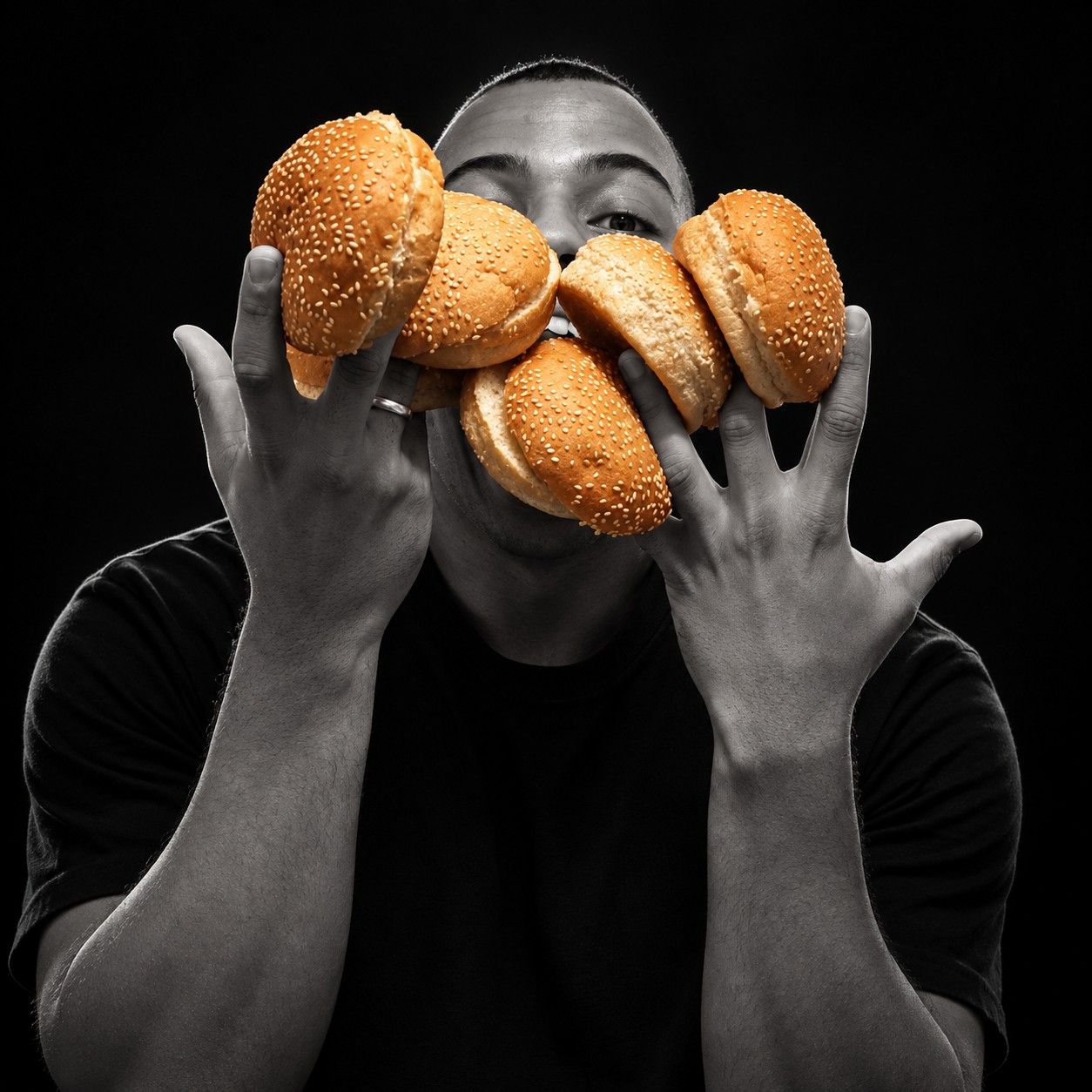 Hiago Carmo segurando pães de hambúrguer dourados na frente do rosto